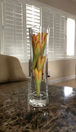 Vase with green and orange imitation flowers inside.
