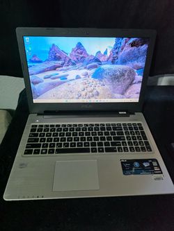 Silver ASUS Ultrabook laptop with a full-size keyboard including numpad, Intel Core i7 processor, and Windows installed. Powers on and boots to deskto