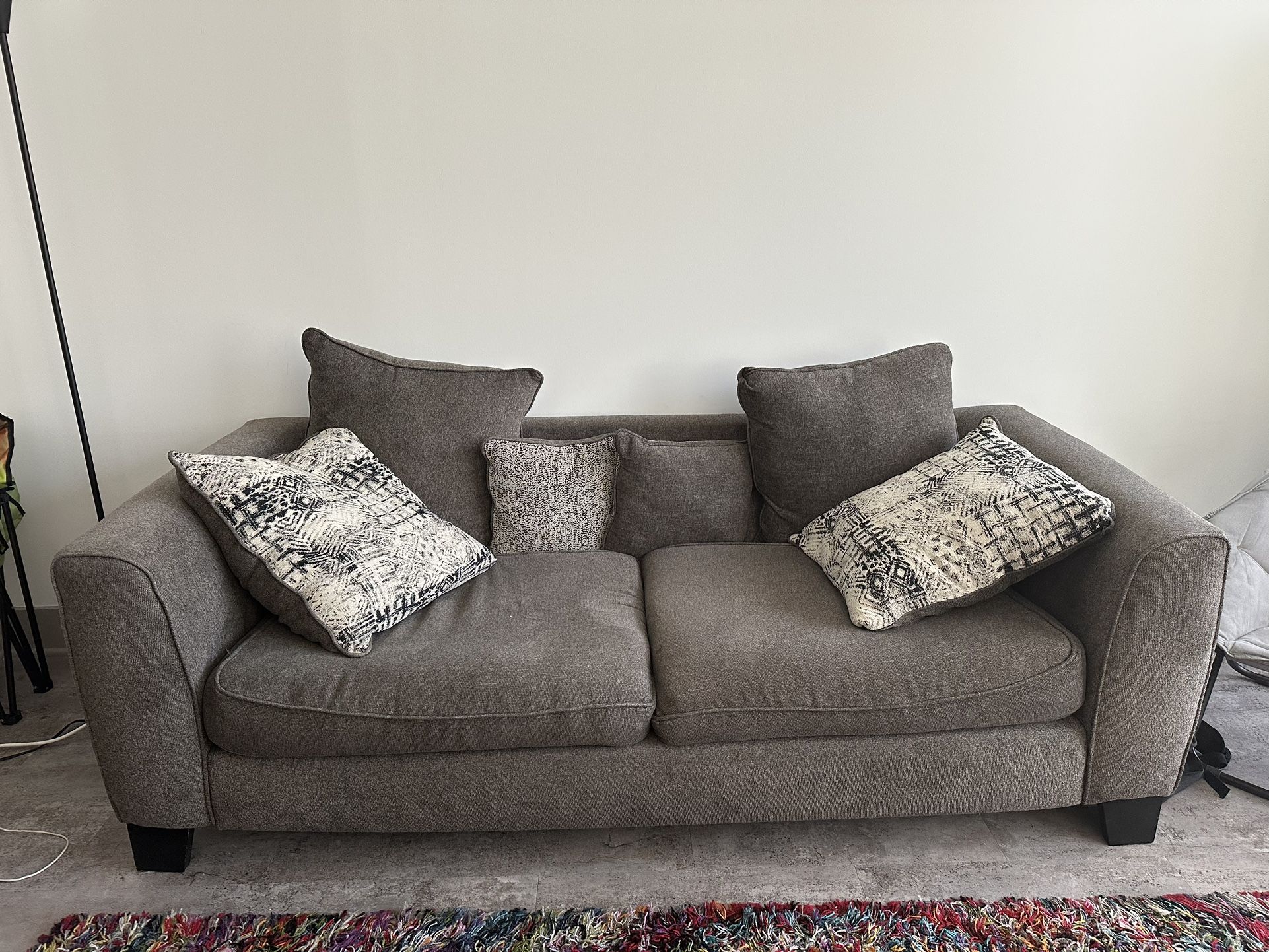 Gray fabric two-seater sofa with decorative throw pillows