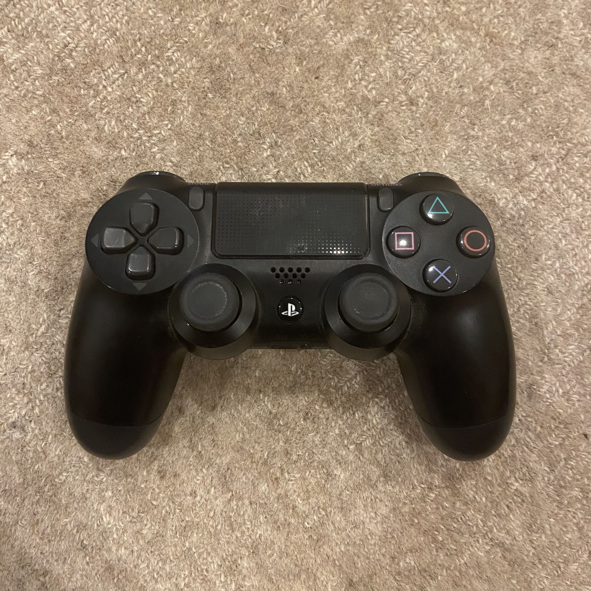 Black PS4 DualShock controller with classic buttons, touchpad, and analog sticks.