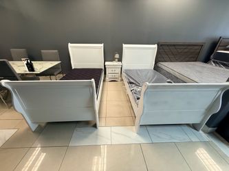 Two white twin bed frames with mattresses