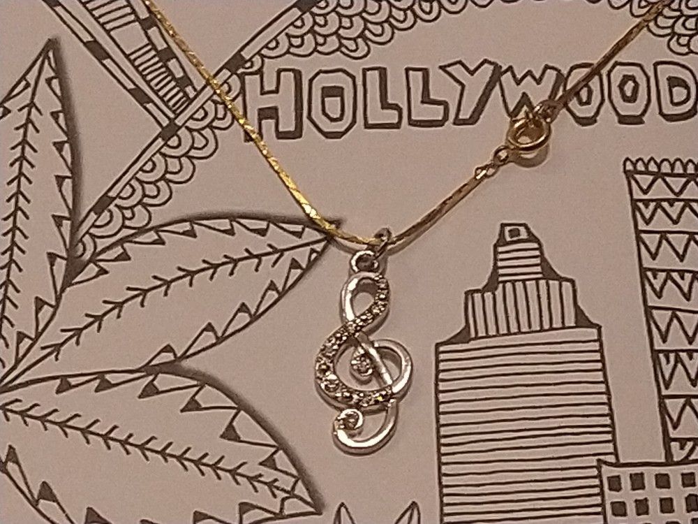 18 inch Gold Toned Necklace With Silver toned Music Note Charm.