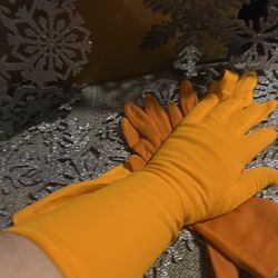The product is 2 pair of vintage women's dress gloves in shades of orange measuring 14”and 9.5 inches in length respectively. Made of polycotton mater