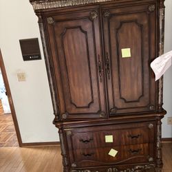 a wooden armoire or wardrobe cabinet, specifically in a traditional or antique-style design.