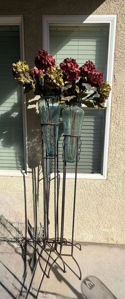 Two large glass vases with iron stands