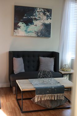 living room set. Includes loveseat, pillows, canvas painting, side table, center table, and decor.