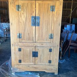 This is a solid wood armoire or wardrobe with metal hardware