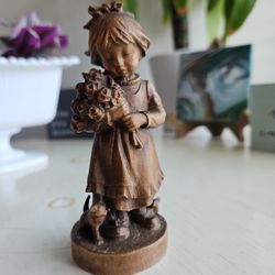 Vintage, European Alpine unpainted, natural wood carving of a little girl holding a bouquet of roses with a kitten and mouse playing at her feet.