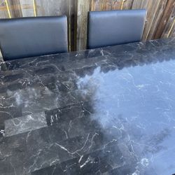 Elegant black marble dining table with two matching chairs.