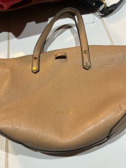 tan or beige textured faux-leather or leather tote handbag by Calvin Klein with gold-tone hardware and a pull-through strap closure detail on the fron