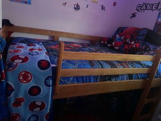 Sturdy wooden loft bed has a natural finish and includes a built-in slide. The frame is constructed from solid wood with a slatted guardrail for safet