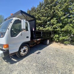 1998 Isuzu NPR Truck with Dump Bed  14’ long x 7’ 3” wide dump bed with barn doors on rear  5.7 L gas engine with automatic transmission  8 cylinders 