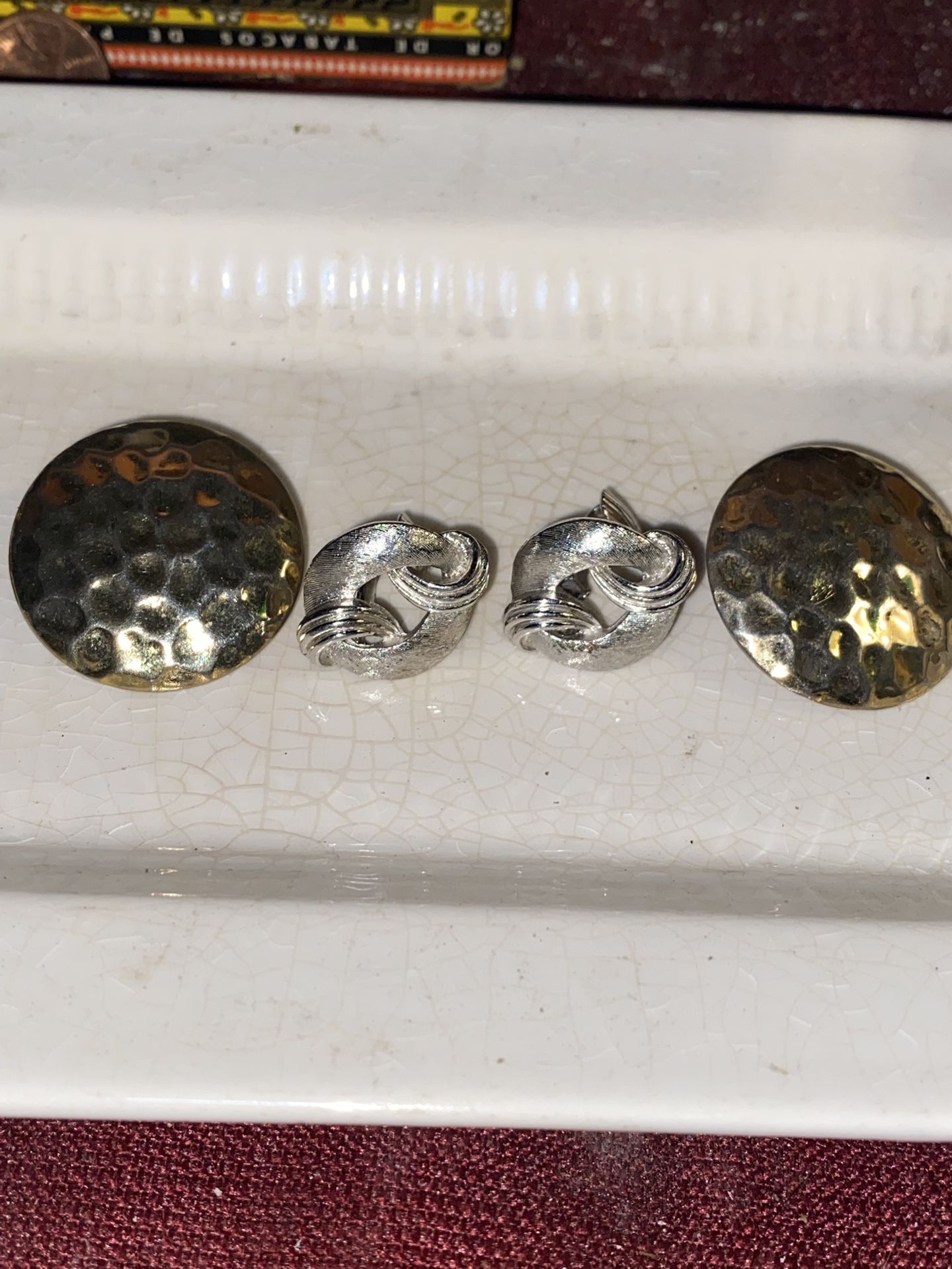 Two vintage pair of earrings one pair is a size of a half dollar go tone. The other is clip on silver with the makers’s name stamped on it.