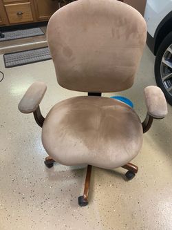 Ergonomic swivel office chair has tan microfiber upholstery and a five-point wooden base.