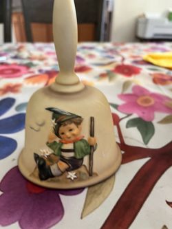 Gobel figurine of a young man sitting on a pile of dirt, holding a stick in his hand