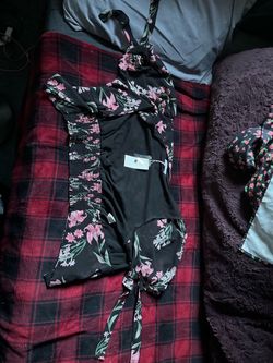 This black floral chiffon swimsuit cover-up features a vibrant pink lily print and a smocked elastic side panel.