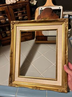 Vintage gold-toned ornate wooden frame with interior linen mat board