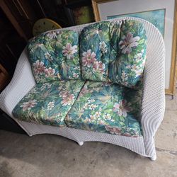 White Wicker Loveseat with Floral Cushions. 