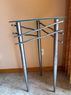 distinctive vintage modern glass-top table with a sculptural silver-tone metal base.