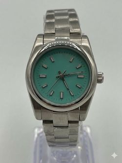 Elegant women's silver watch featuring a beautiful turquoise dial.   /    Reloj para dama con elegante acabado plateado y esfera color turquesa.