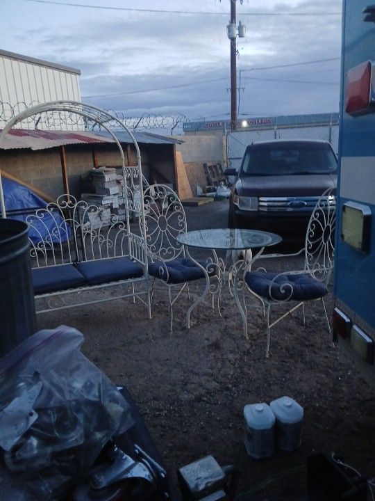Vintage wrought iron patio set two chairs a table with a glass top for the table and a bench with an arch