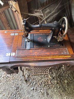Vintage sewing machine in cabinet with metal pedestal foot