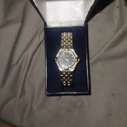 This is a Gruen ladies' watch,  model GR7371, with a black face and crystal-accented bezel and a gold-toned or silver-plated bracelet band.