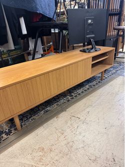 oak TV stand features a modern fluted design and sliding doors - 63” x 15” x 18”