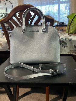 The bag is the Michael Kors Cindy Dome Satchel in a striking metallic silver finish, featuring practical top handles and an adjustable strap.