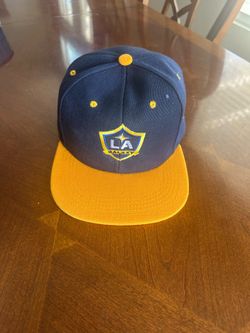 LA Galaxy fanatics batters box snapback hat features a navy crown with a contrasting yellow flat brim and embroidered team logo