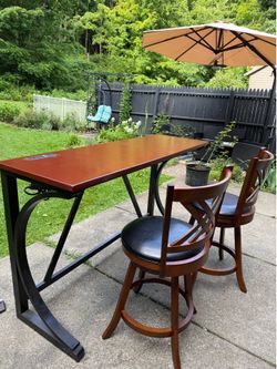 Bar table with two solid wooden chairs.