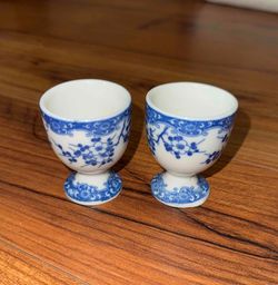 A pair of blue and white porcelain Japanese egg cups with cherry blossom motifs.