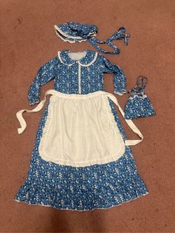 Charming blue floral prairie dress with matching bonnet and purse pouch. Includes a removable white apron for authentic play. Fits about 10 to 11 ye
