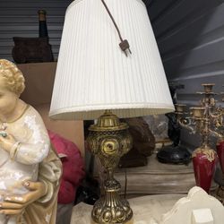 Ornate brass-toned table lamp with pleated shade.