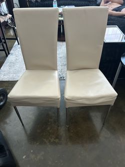 Set up four white leather dining chairs