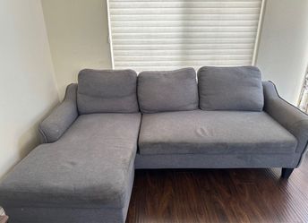 Gray upholstered chaise lounge with a back cushions and rolled armrest. Some light wear and indentations visible on the seat cushion. Make an offer