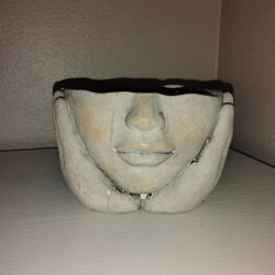 Filled Ceramic Candle features a woman's face and hands