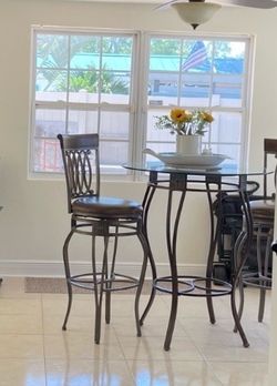 High top table with a glass and two chair