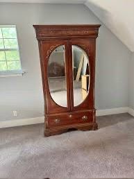 Vintage Pulaski Furniture armoire featuring distinctive oval mirrored doors, dark wood finish, and decorative carving