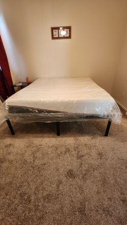 California king mattress (in plastic) with black metal platform bed frame