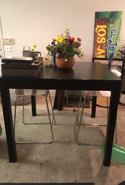Black high dining table with two tall white chairs