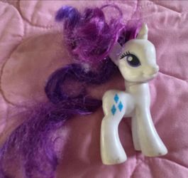 white Hasbro My Little Pony Rarity G4 brushable toy figure with large blue eyes and a purple mane and tail.