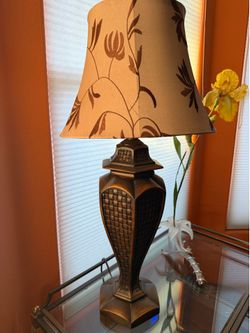 Regency Hill traditional urn-style table lamp featuring a distressed bronze base and a beige bell shade.