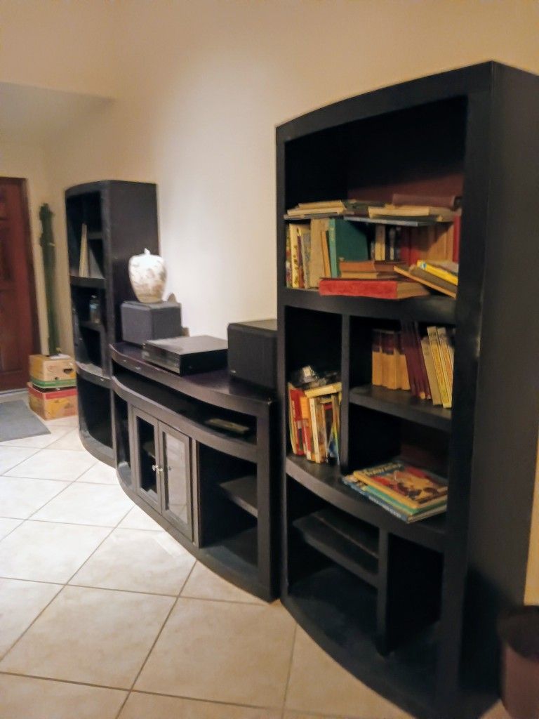 Black entertainment center with center pc. and 2 bookshelves/ends with multiple shelves and storage space. Solid wood.