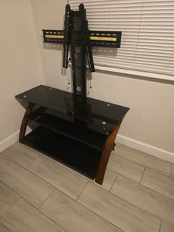 black tempered glass TV stand with three shelves and an integrated mounting bracket.
