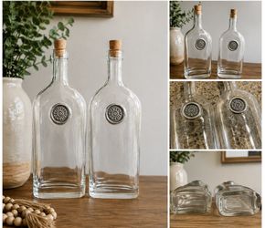 Set of 2 Decorative Glass Bottles with Cork Stoppers Beautiful matching set of 2 clear glass bottles. Each features a unique embossed medallion with a