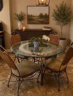Bassett wrought iron dining set features four woven wicker chairs with a matching round glass-top table base (Delivery Available)