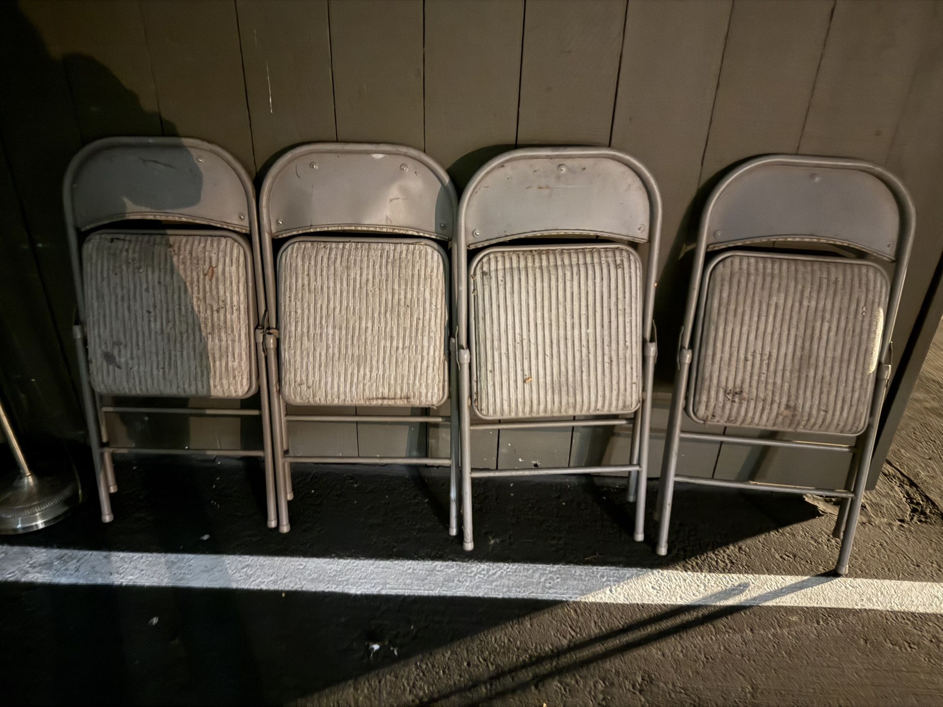 Four metal folding chairs with upholstered seats.