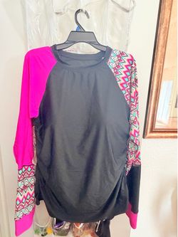 Woman’s long sleeve  rash guard top in black with vibrant pink and geometric patterned sleeves .
