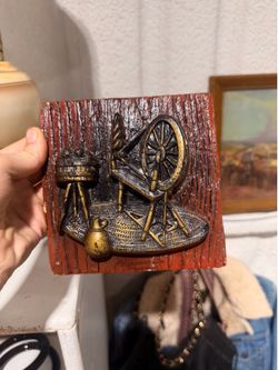 A 3D gold-painted spinning wheel and butter churn relief wall plaque